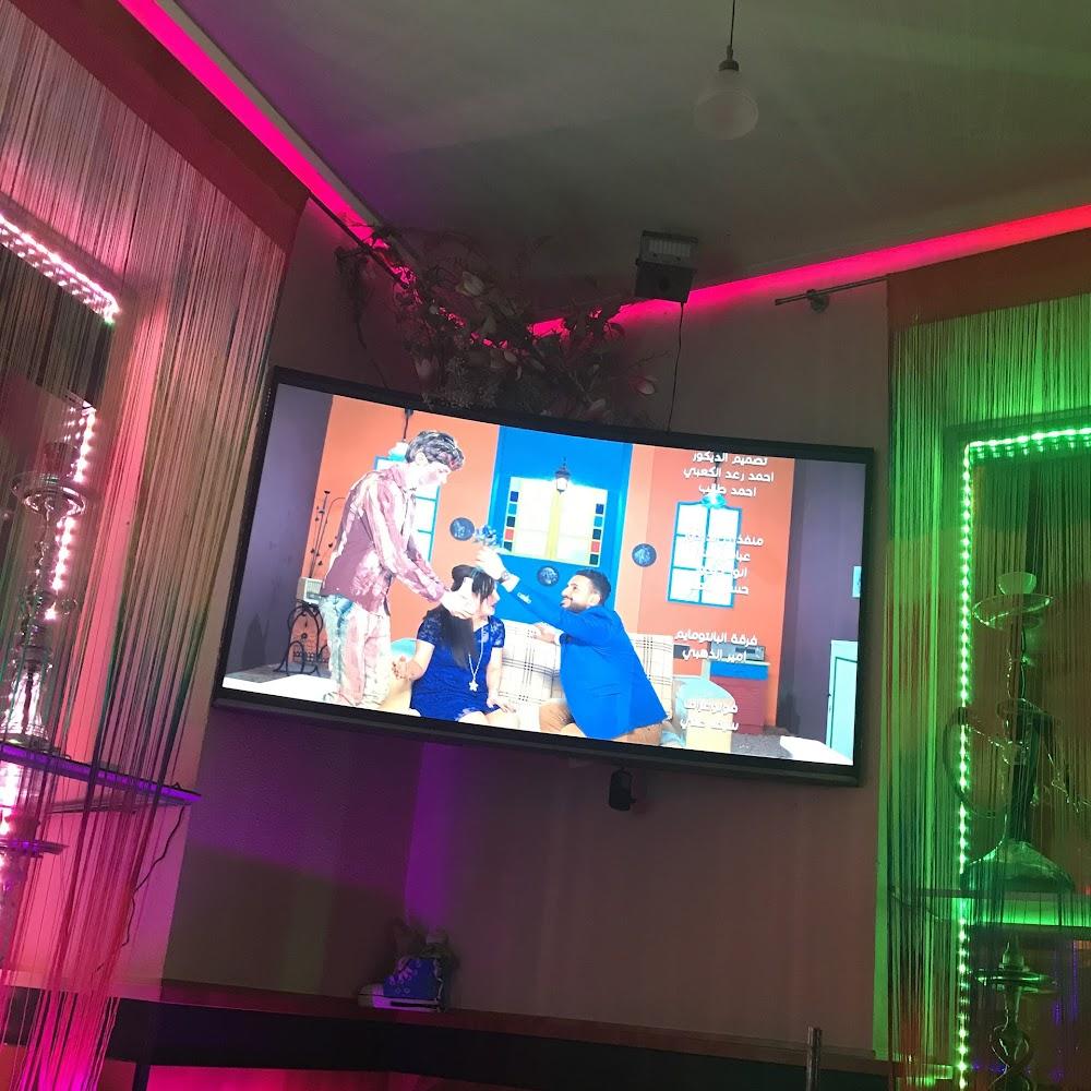 TV screen with people on it, a hookah, and pink and green curtains.